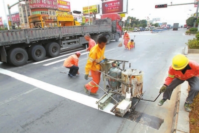 工人在用手推熱熔劃線機(jī)施劃標(biāo)線